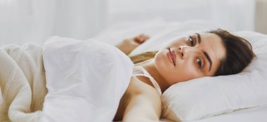 Güzel bir kadın yatağında uzanıyor..