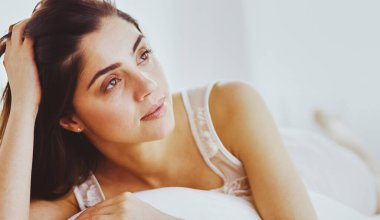 Güzel bir kadın yatağında uzanıyor..