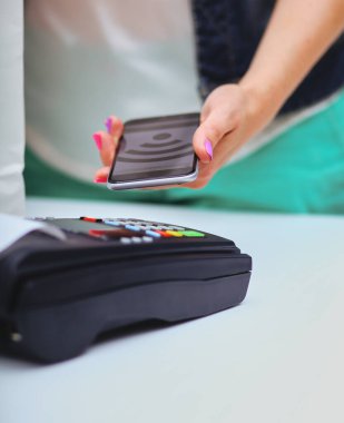 Müşteri ile smartphone Nfc teknolojisi kullanılarak dükkanda ödüyor. NFC teknolojisi. Müşteri ödeme.