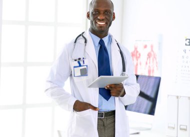 Tablet bilgisayarlı siyahi bir doktor hastanede bekliyor..