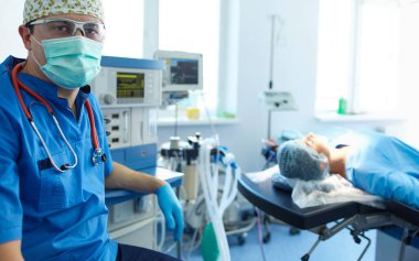 Ameliyat odasında arka planda erkek cerrah var..