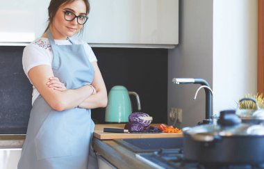 Yeni mutfakta yemek pişiren kadın sebzelerle sağlıklı yemekler yapıyor..