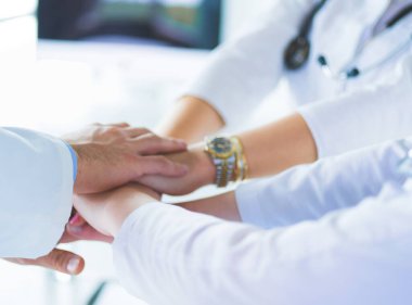 Doktorlar ve hemşireler tıbbi bir ekipte el ele tutuşuyorlar..