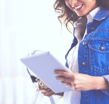 Gülümseyen kadın kahve içiyor ve kafede tablet kullanıyor.