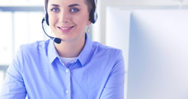 Ofisinde kulaklık takmış, telefon operatörü olarak çalışan ciddi ve güzel bir genç kadın..