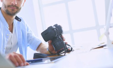 İnternette çalışırken bilgisayarın ve dizüstü bilgisayarın önünde grafik stüdyosunda oturan genç tasarımcının portresi