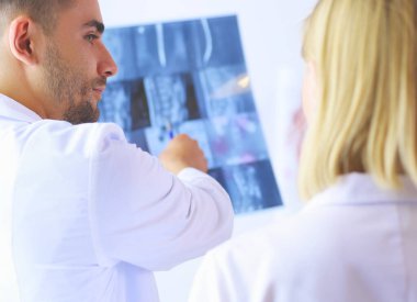 Yakışıklı doktor genç bayan doktorla konuşuyor ve ofisinde otururken notlar alıyor.