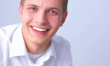 Gri arka plan üzerinde oturan genç adam portresi