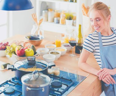 Mutfakta masanın yanında duran genç bir kadın. .