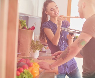 Bir çift evdeki mutfaklarında birlikte yemek pişiriyor..