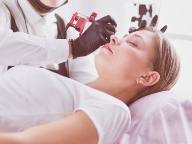 Mikro patenli kaşlar güzellik salonunda çalışır. Kaşları renkli bir kadın..