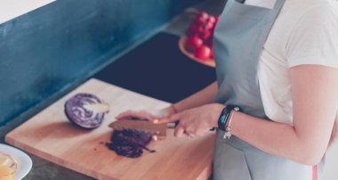 Mutfakta yemek yapmak için tablet bilgisayar kullanan genç bir kadın..