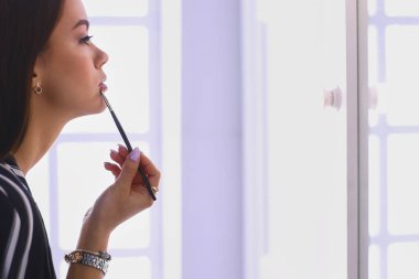 Genç kadın ruj bir ayna önünde uygulama.