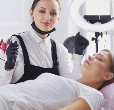 Mikro patenli kaşlar güzellik salonunda çalışır. Kaşları renkli bir kadın..