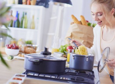 Evdeki mutfakta yemek pişiren güzel genç bir kadın..