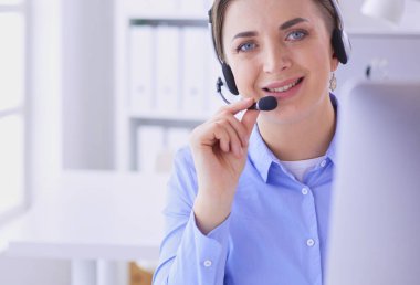 Ofisinde kulaklık takmış, telefon operatörü olarak çalışan ciddi ve güzel bir genç kadın..