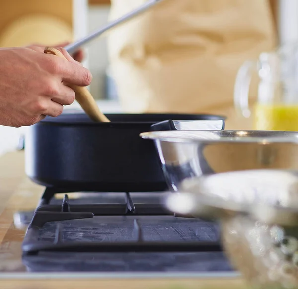 Man following recipe on digital tablet and cooking tasty and healthy food in kitchen at home.