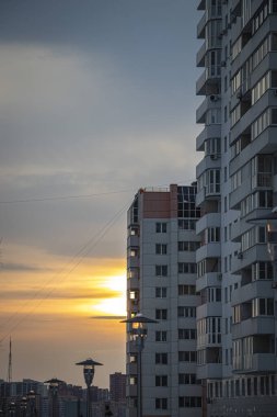 Büyük bir sanayi şehrinin arka planına karşı güzel bir günbatımı. Batan güneşin ışınları sokak lambalarına yansıyarak rahat bir atmosfer yaratıyor.. 