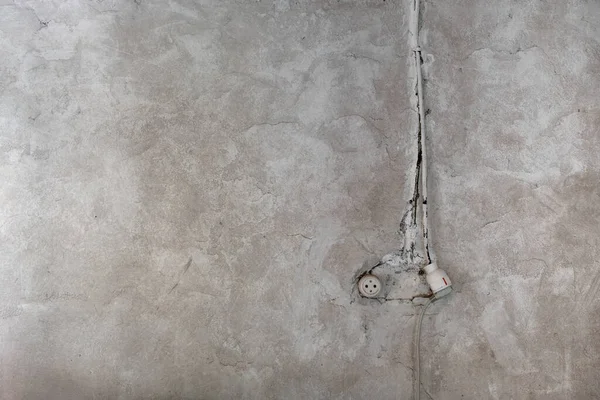 Rustic electrical socket on old limewashed plaster wall, indoor architecture detail, grunge background