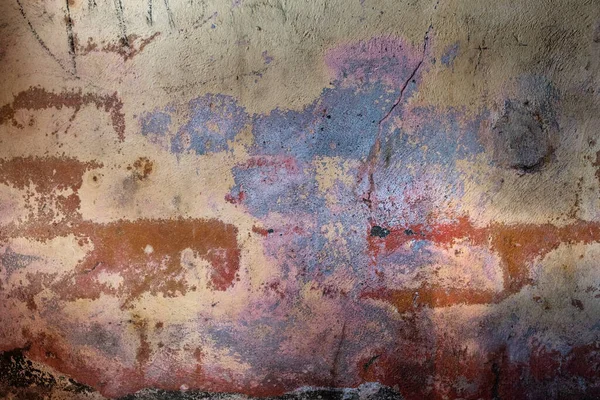 Old distressed wall with damp and worn out layers of pastel colors paint, grunge background or texture