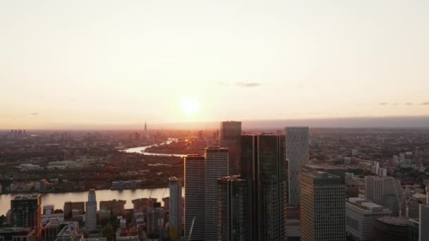 Luftaufnahmen von Wolkenkratzern im modernen Geschäftsviertel Canary Wharf. Die Themse fließt durch die Stadt. Blick gegen die untergehende Sonne. London, Großbritannien — Stockvideo