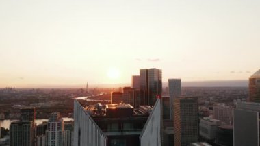 Fütürist yüksek binanın tepesine uç. Canary Wharf ilçesindeki gökdelenlerin manzarası yükseldi. Gün batımına karşı şehir manzarası. Londra, İngiltere