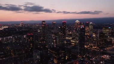 Akşam şehrin kayarak ve panoramik görüntüsünü kaydır. Akşam karanlığında şehir manzarası. Canary Wharf bölgesindeki büyük ticari bina. Londra, İngiltere