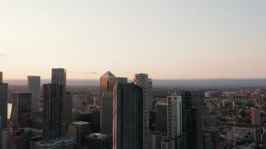 Şehirdeki diğer binalardan yüksek gökdelenlerin etrafında uç. Parallaks etkisi. Canary Wharf 'ın akşam görüntüsü. Londra, İngiltere