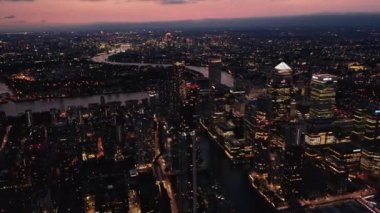 Geceleri şehrin hava panoramik görüntüleri. Canary Wharf İş Merkezi 'ndeki gökdelenler One Canada Meydanı' nın en çok aydınlatılan piramit çatısı. Akşam karanlığında şehir manzarası. Londra, İngiltere