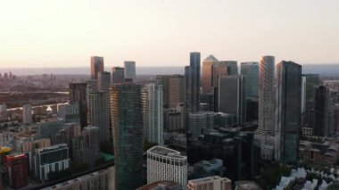 Canary Wharf 'ın finansal ve ekonomik merkezindeki gökdelenlerin hava görüntüsü iniyor. Günbatımı ile aydınlanan modern şehir bölgesi. Londra, İngiltere