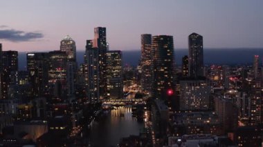 Akşamları Canary Wharf 'ın fütürist bölgesinde modern yüksek ofis ve konut binalarının kaydırma ve tavana yükseltilmiş görüntüsü. Şehir ışıkları su yüzeyine yansıyor. Londra, İngiltere