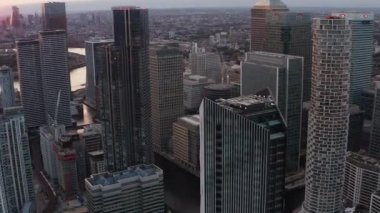 Fütürist kentsel bölgenin kaydırak ve pan görüntüleri. Gün batımında Canary Wharf iş merkezindeki büyük ofis ve apartman binaları. Londra, İngiltere