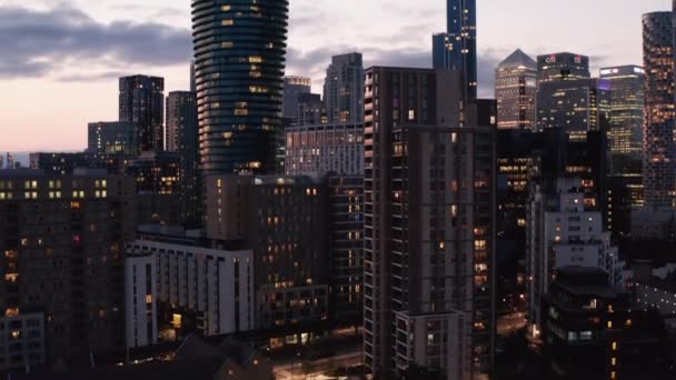 Rising shot of modern downtown skyscrapers in Canary Wharf business hub after sunset. Evening footage against pink twilight sky. London, UK — Stock Video