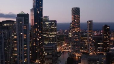 Canary Wharf İş Merkezi 'ndeki gökdelenlerin alacakaranlık gökyüzüne karşı ters açılışı. Gün batımından sonra pencereler aydınlandı. Londra, İngiltere