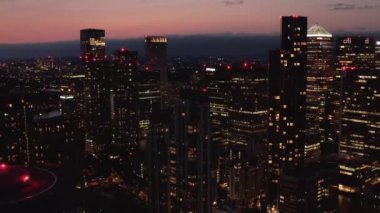 Günbatımında Canary Wharf 'taki aydınlık gökdelenlerin modern finansal ve ekonomik merkezlerini ortaya çıkarıyor. Gece şehri sahnesi. Londra, İngiltere