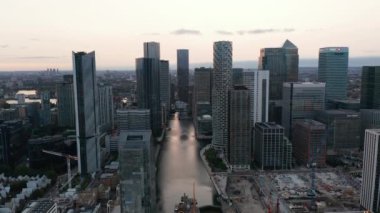 Eski rıhtımlardaki su kanalı boyunca modern ofis binaları. Gün batımından sonra Canary Rıhtımı 'nda ikonik gökdelenler. Londra, İngiltere