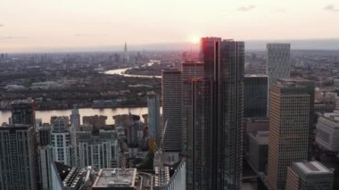 Canary Wharf İş Merkezi 'ndeki yüksek gökdelenler grubunun etrafında uçuyorlar. Gün batımında şehrin havadan panoramik görüntüsü. Londra, İngiltere