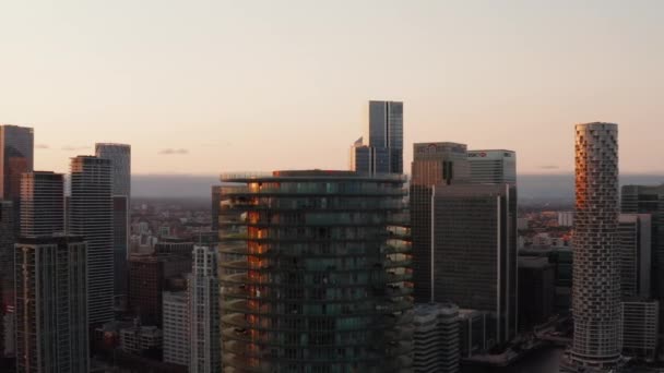 Skjut och panorera bilder av toppen av Baltimore Tower. Cylindrisk lägenhet byggnad med terrasser på ringar runt. Skyskrapor i Canary Wharf stad och stadsbild i solnedgången tid. London, Förenade kungariket — Stockvideo
