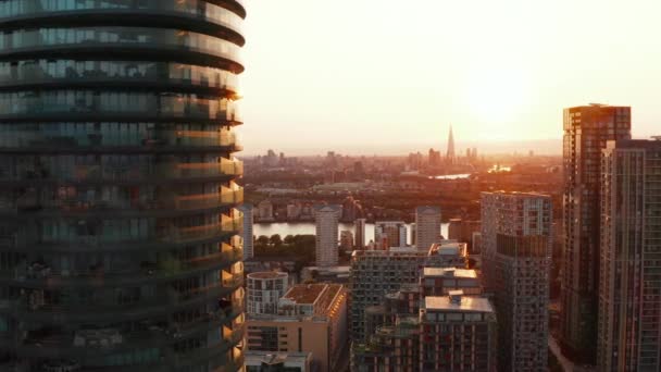 Vola intorno all'alto edificio residenziale cilindrico moderno Arena Tower nel quartiere Canary Wharf. Quartiere della città futuristico al tramonto. Londra, Regno Unito — Video Stock