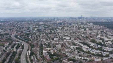 Şehir manzarasının havadaki panoramik kayma görüntüsü. Taşımacılık altyapısı yerleşim bölgesinden geçiyor. Londra, İngiltere