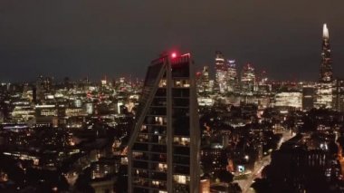 Modern yüksek apartman kulesinin yükselen görüntüsü. Arka planda gökdelenleri olan şehir manzarası. Londra, İngiltere