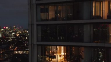 Geceleri modern yüksek konut binasında lüks bir daire. Pencerelerin görüntüsünü kapat. Turna yukarı. Londra, İngiltere