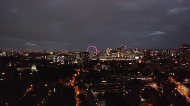 Κατεβαίνοντας πλάνο του νυχτερινού αστικού τοπίου. Αστική γειτονιά τη νύχτα. Φωτισμένο London Eye εξ αποστάσεως. Λονδίνο, Ηνωμένο Βασίλειο — Αρχείο Βίντεο