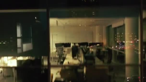 Szybko wznoszący się strzał w nocy wzdłuż okien biurowych. Mętny film z oświetlonymi pustymi biurami z zewnątrz. Londyn, Wielka Brytania — Wideo stockowe
