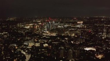 Geceleri büyük şehrin havadan panoramik görüntüsü. Şehir ışıkları karanlığa doğru parlıyor. Şehir merkezinin üzerinden uç. Londra, İngiltere