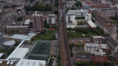 Şehir merkezindeki çok kanallı demiryolu hattının havadan görüntüsü. Eğilin ve yolcu trenini takip edin. Londra, İngiltere