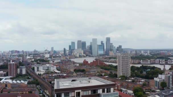 Flygfoto panoramautsikt över stadsdelen på Thames rive bank och skyskrapor i Canary Wharf finansiella centrum. Gömmer sig gradvis bakom ett hyreshus. London, Förenade kungariket — Stockvideo