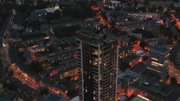 Inclinación de imágenes de One The Elephant casa de apartamentos de altura. Edificios modernos de gran altura contra el desarrollo en el barrio urbano por la noche. Londres, Reino Unido — Vídeo de stock