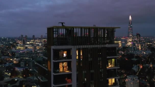 Latać nad górnym tarasem wysokiego budynku mieszkalnego. Ujawniający panoramiczny widok na nocny pejzaż z drapaczami chmur w centrum miasta. Londyn, Wielka Brytania — Wideo stockowe