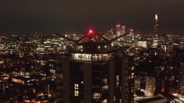 背の高いアパートの建物で屋上の展望テラスの周りを飛ぶ。街のパノラマと夜のシーン。イギリスのロンドン — ストック動画